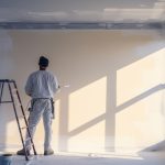 painter male worker paints a wall with a paint roller Repainting the walls inside the house